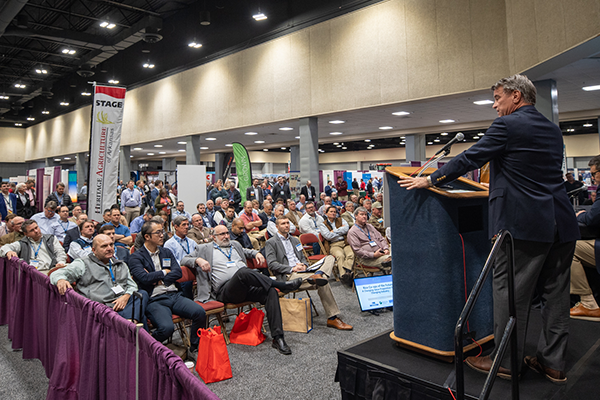 A speaker addresses a crowd of conference attendees