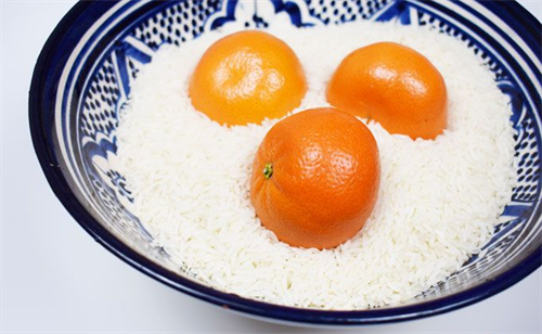 Close up view of three clementines  in a bowl of raw rice.