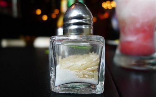 Side view of a glass salt shaker with raw rice grains to prevent salt clumps.
