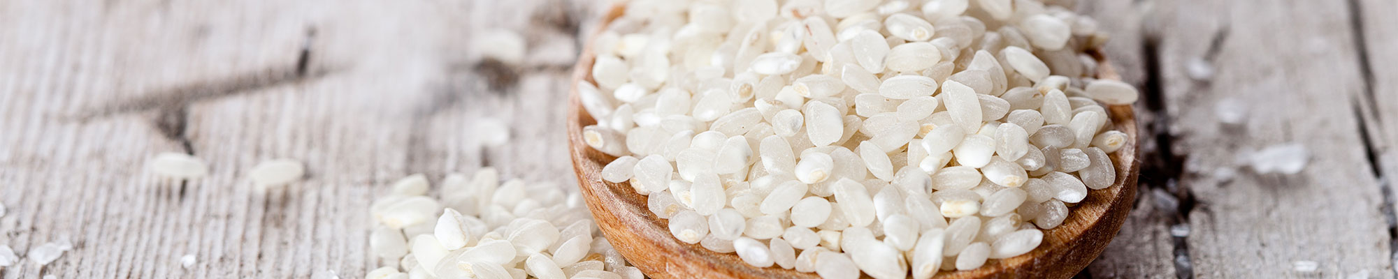 A scoop of rice on a wooden table.