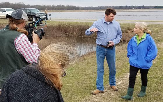 Sara-Moulton-&-Eric-Vaught being filmed while walking next to flooded rice fields