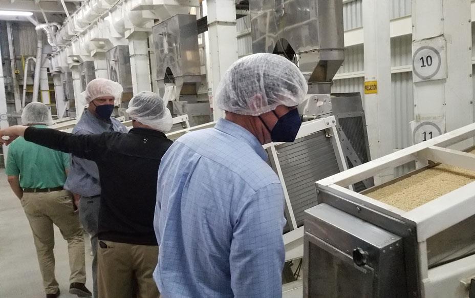 Mill-tour, people wearing face masks & hairnets looking at milling equipment
