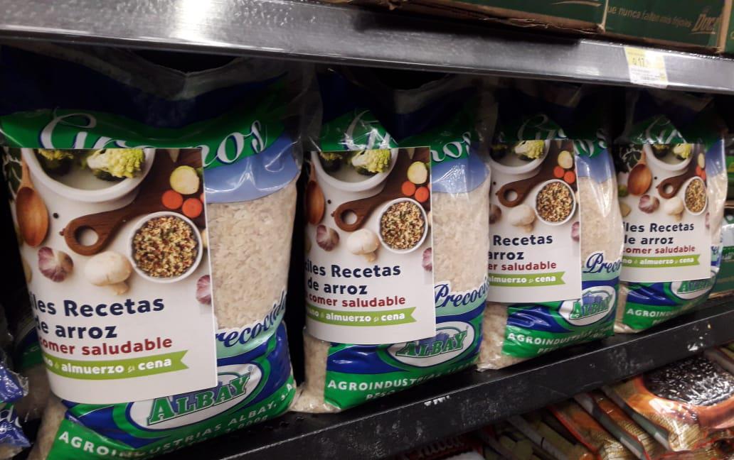 Recipe books on bags of rice stacked on grocery store shelves