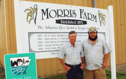 Two men stand in front of Morris Farm sign