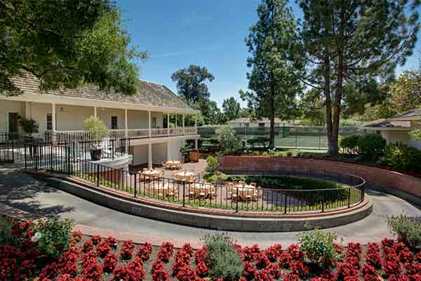 Walkway overlooking a courtyard set up with tables and chairs for dining.