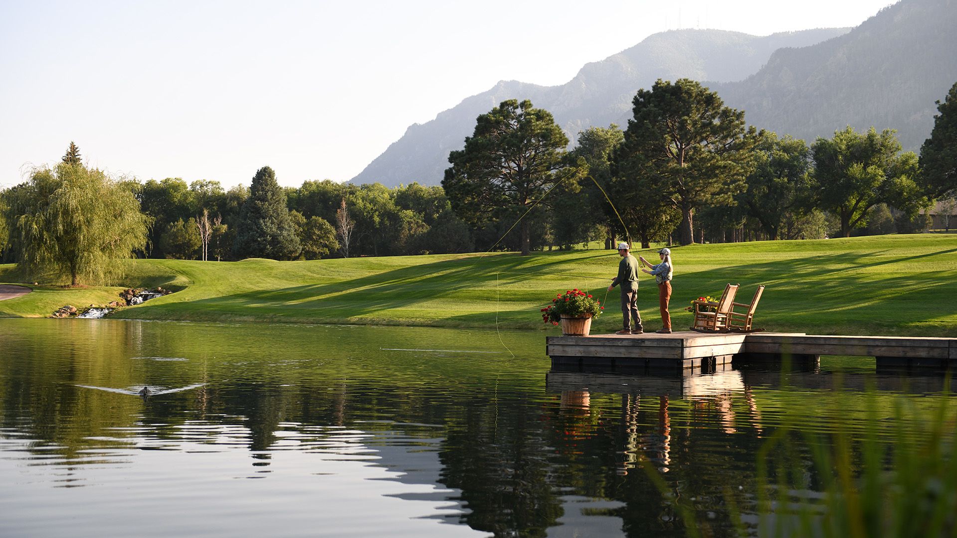 People fishing with trees and mountains in background
