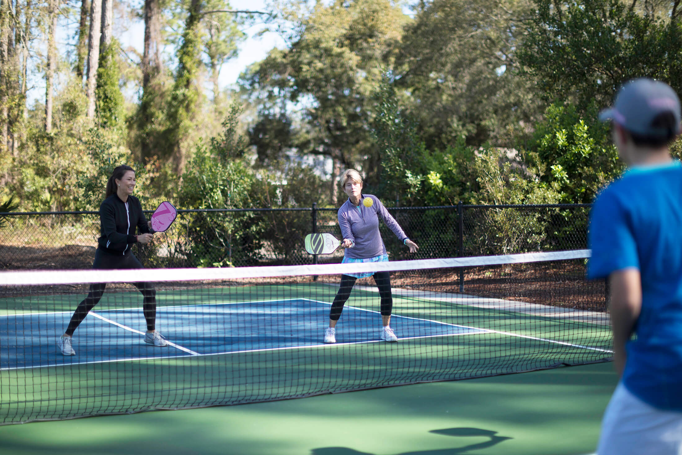 Three people playing pickleball
