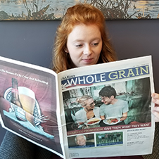 Image of a girl reading the Whole Grain newspaper