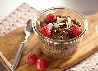 Side view of chocolate espresso rice porridge in a glass dish topped with berries.