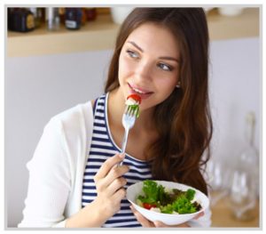 Image of a young woman eating a salad.