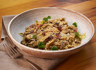 Side view of Fall Mushroom Risotto in a white bowl.