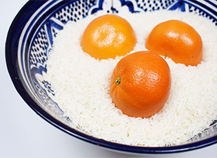 Close up view of three clementines  in a bowl of raw rice.