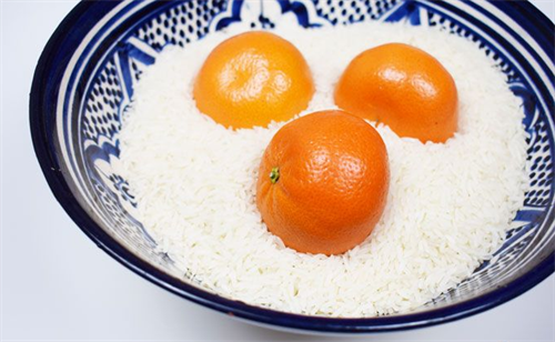 Ripen Fruit Close up view of three clementines in a bowl of raw rice.