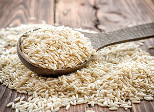 Wooden spoon full of whole grains on top a bed of whole grains.