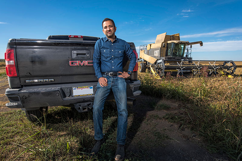 Rice farmer, Imran Khan, standing in front of a truck with combine in background.