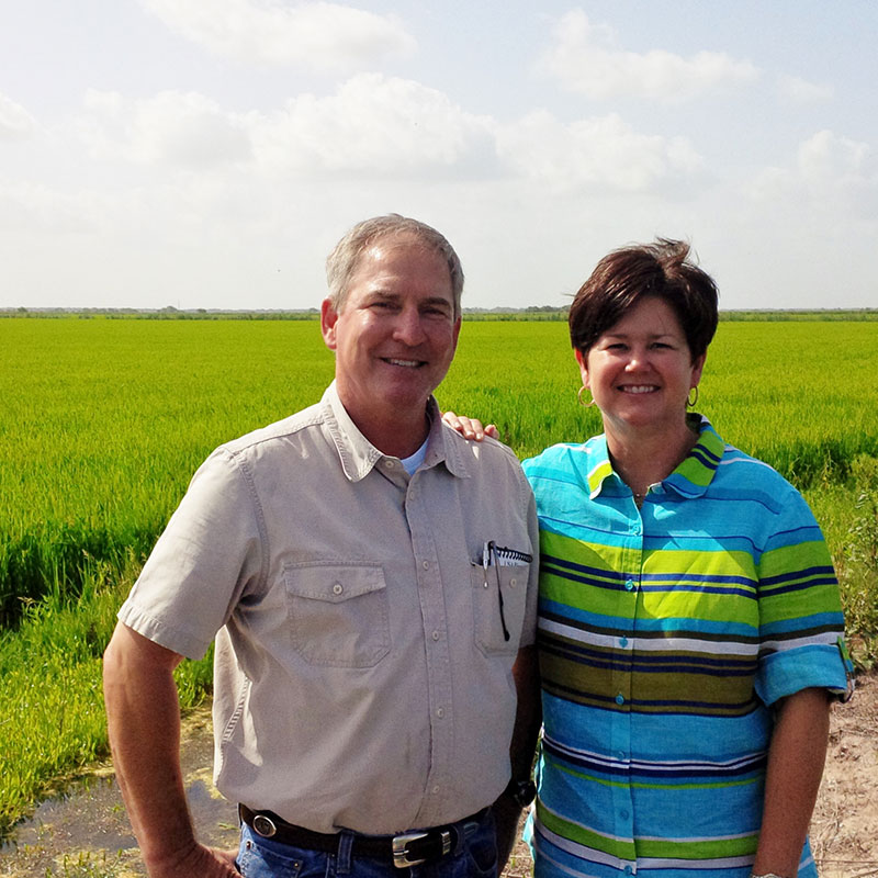 Linda and LG Raun in front of a rice field.