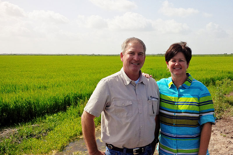 Linda and LG Raun in front of a rice field.