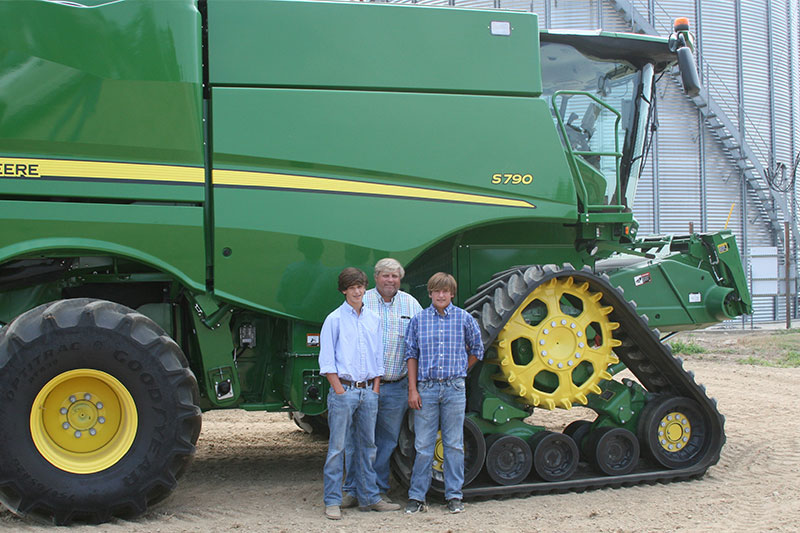 Rice farmer, Nat McKnight, standing with sons in front of a combine.