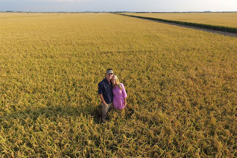 Rice farmer Ryan Sullivan standing in a rice field with his wife.