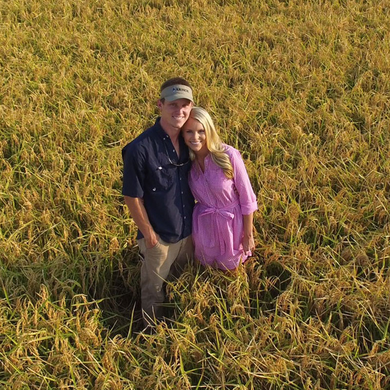 Rice farmer Ryan Sullivan standing in a rice field with his wife.