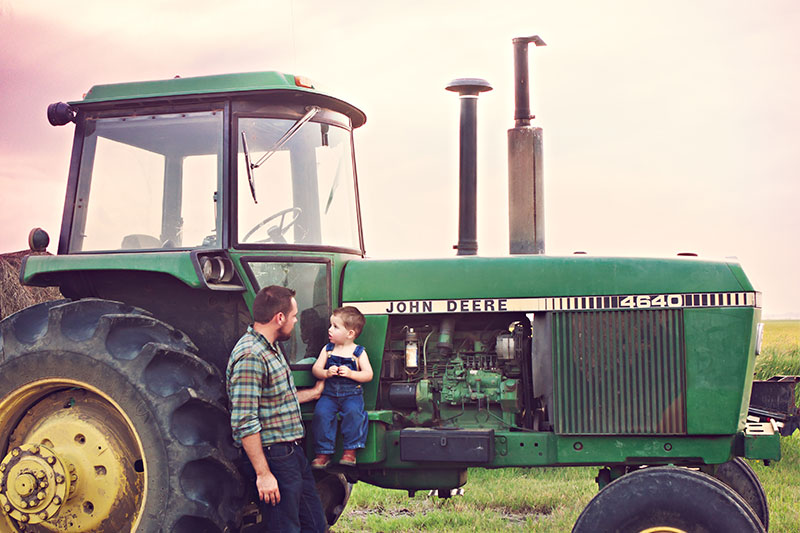 Rice farmer, Zach Worrell, standing in front of an old tractor with his son.