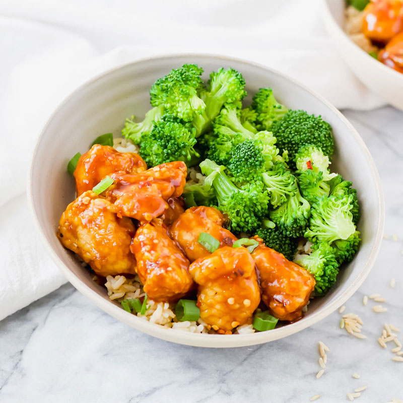 A bowl full of Air Fryer General Tso's Chicken and Rice topped with broccoli. 
