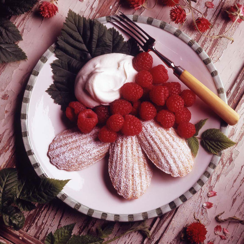 Almond rice madeleines on white plate with raspberries