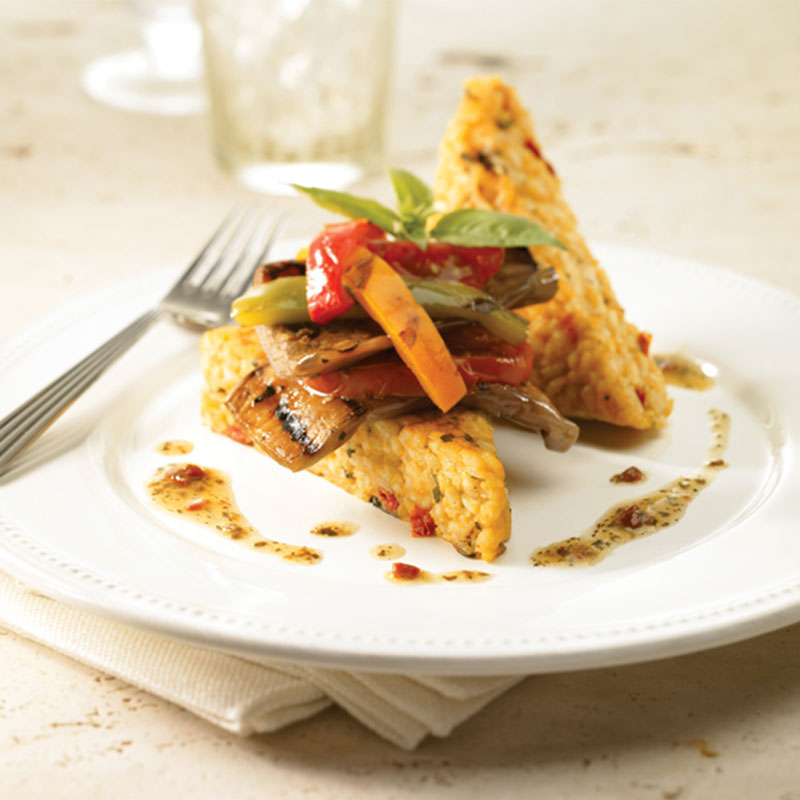 Side view of arboritto rice cakes with grilled vegetables on a white plate.