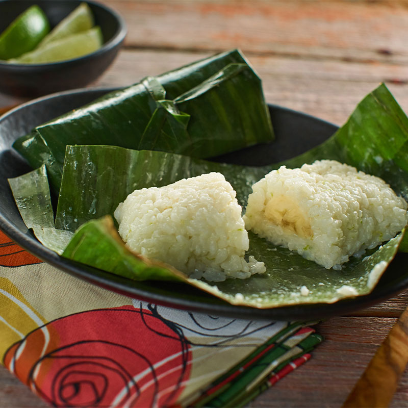 Banana Sticky Rice Banana Sticky Rice cut in half and displayed on an open banana leaf.