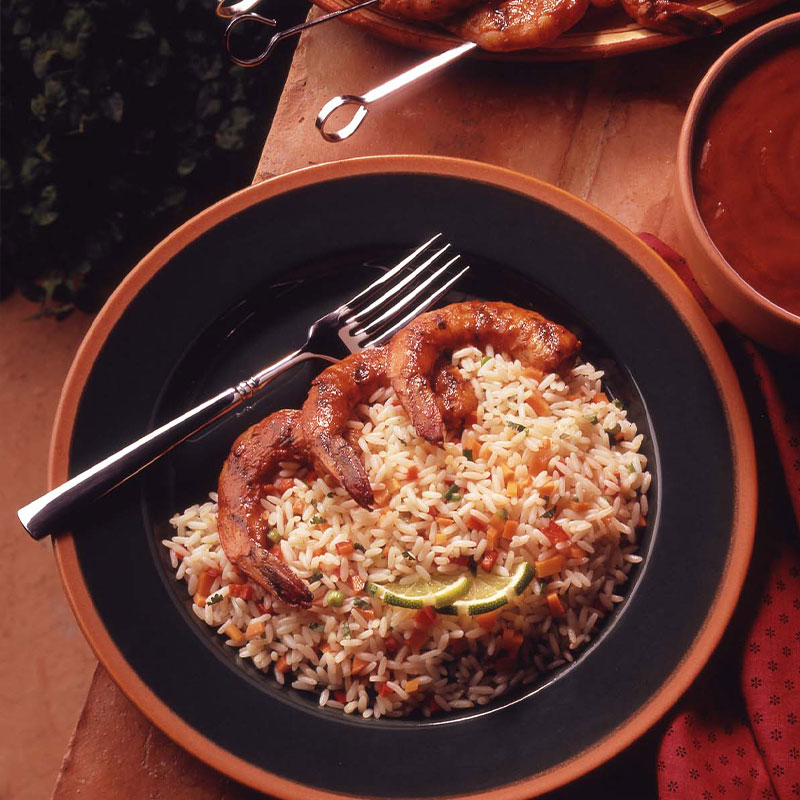 Overhead shot of Barbecued Shrimp with Spicy Rice on a plate with a fork resting to the side.