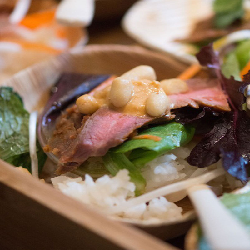 Beef Satay Rice Bowl Individual serving of Beef Satay on top of white rice coupled with various leafy vegetables.