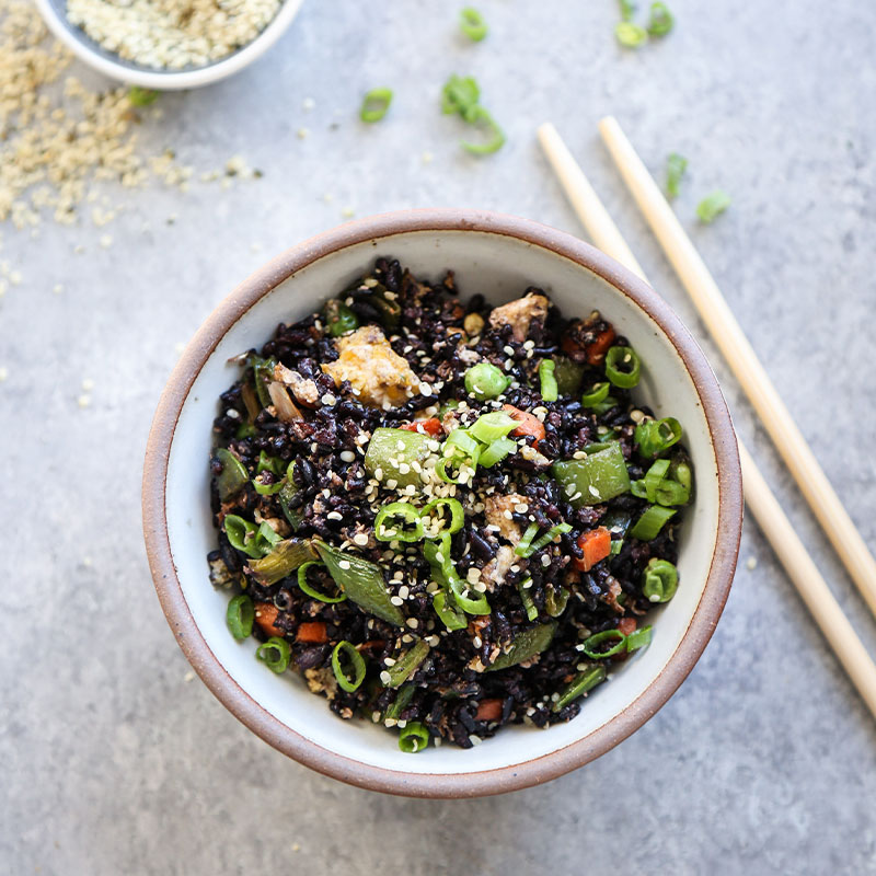 Black Fried Rice with Snap Peas and Hemp-Seeds Overhead shot of Black Fried Rice with Snap Peas in a white bowl.