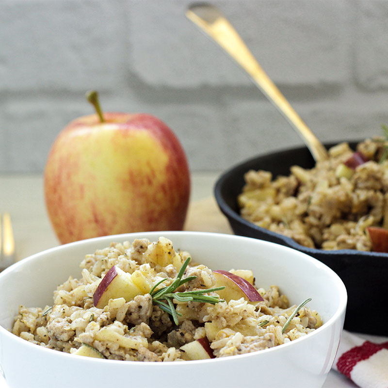 Side profile of a bowl of cinnamon and maple breakfast rice next to a skillet full of the breakfast rice.