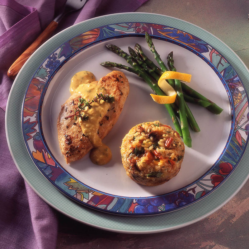 Overhead view of brown rice and mushroom timbales on a plate with chicken breast and asparagus. 