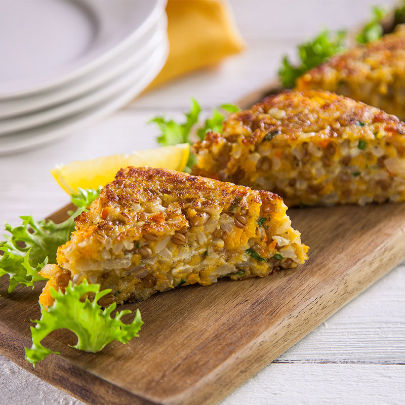 Side view of butternut squash cakes on a wooden serving platter.