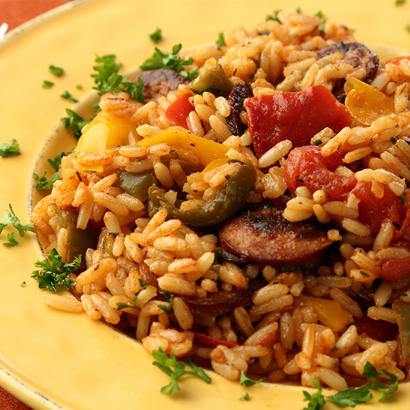 Close up view of Cajun sausage and pepper rice on a yellow plate.