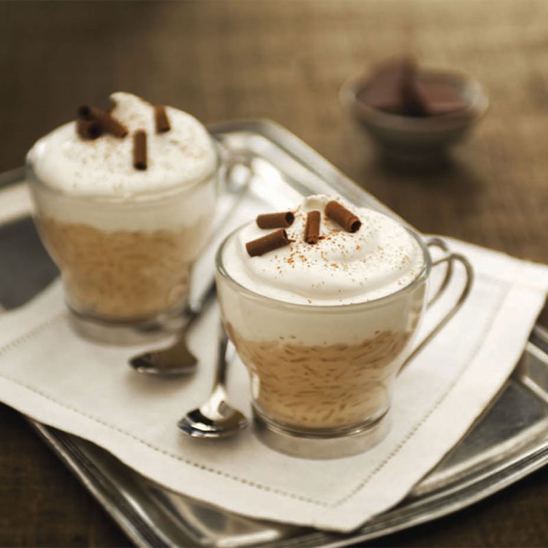 Two Cappuccino Rice Pudding Cups in glasses and topped with whipped cream.