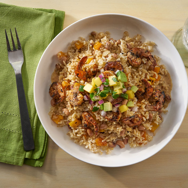 Overhead shot of Caribbean Shrimp and Rice topped with red onion and avocado. 