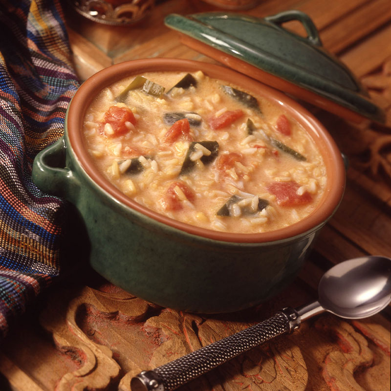 Overhead view of Cheesy Poblano Soup in a green pot.