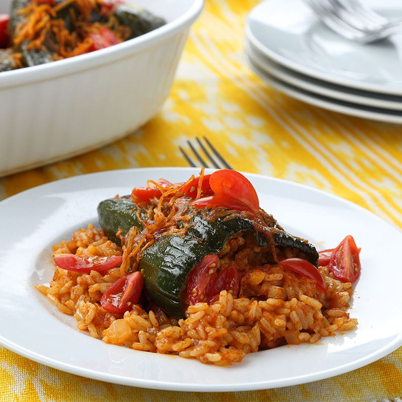 Close up view of cheesy rice poblano chilies on a white plate.