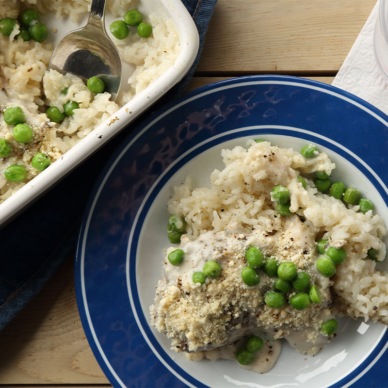 A plate of Chicken & Rice Alfredo next to a serving dish of it.