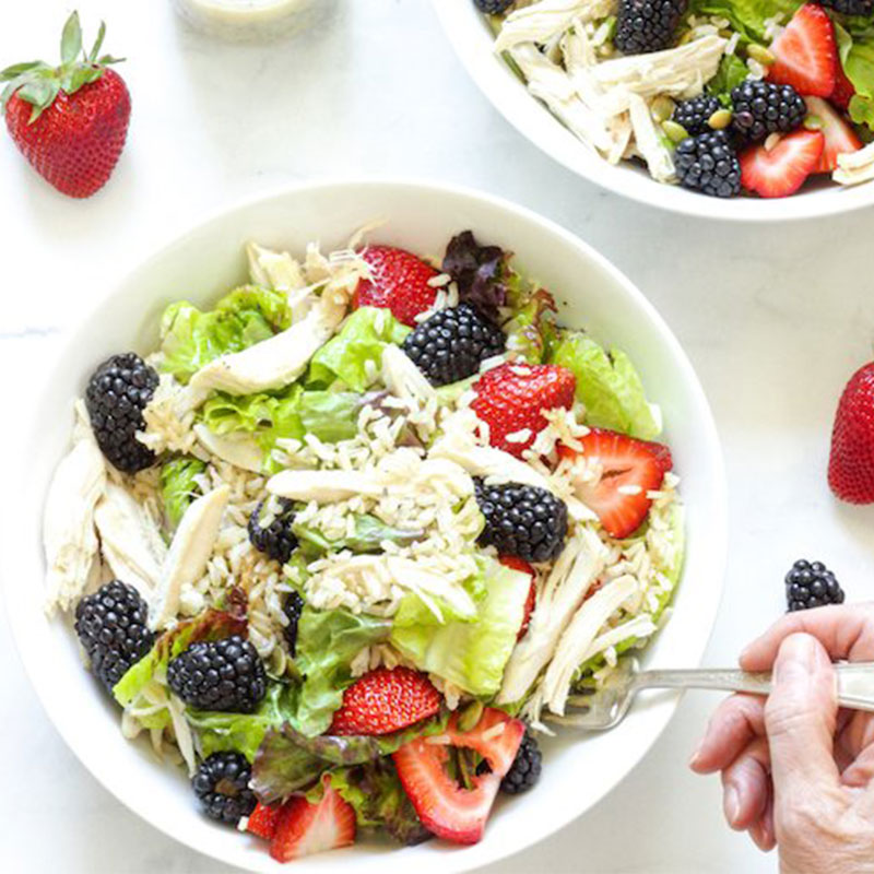 Overhead view of chicken berry and brown rice in a white bowl.