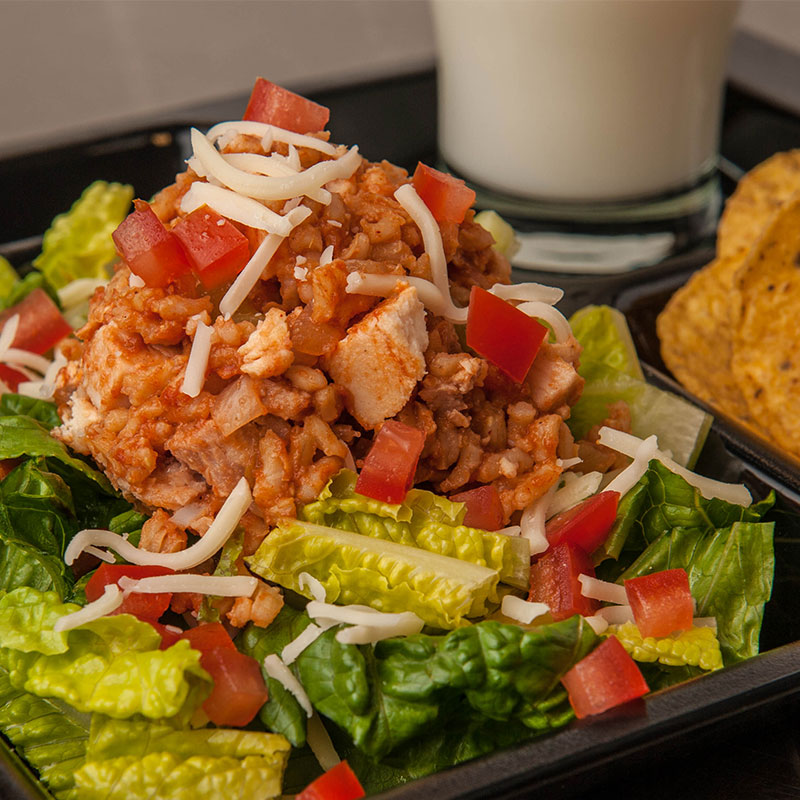 Close up view of Chicken Fiesta Rice Salad on a school lunch tray with tortillas and milk.