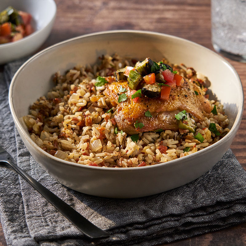 Side view of chicken skin jambalaya in a white bowl.