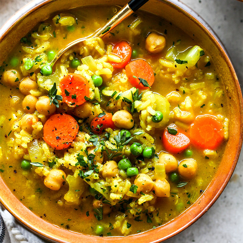Chickpea and Rice Soup Overhead shot of a warm bowl of Chickpea and Rice Soup with peas and carrots exposed.