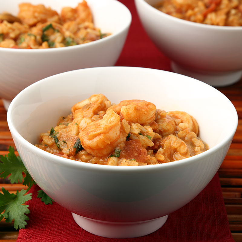 Close up view of coconut curry rice with shrimp in a white bowl.