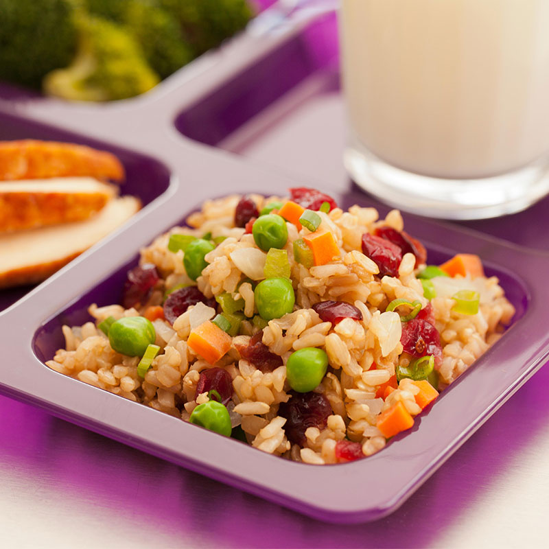 Cranberry Brown Rice with Veggies Close up view of cranberry brown rice with veggies on a purple school lunch tray.
