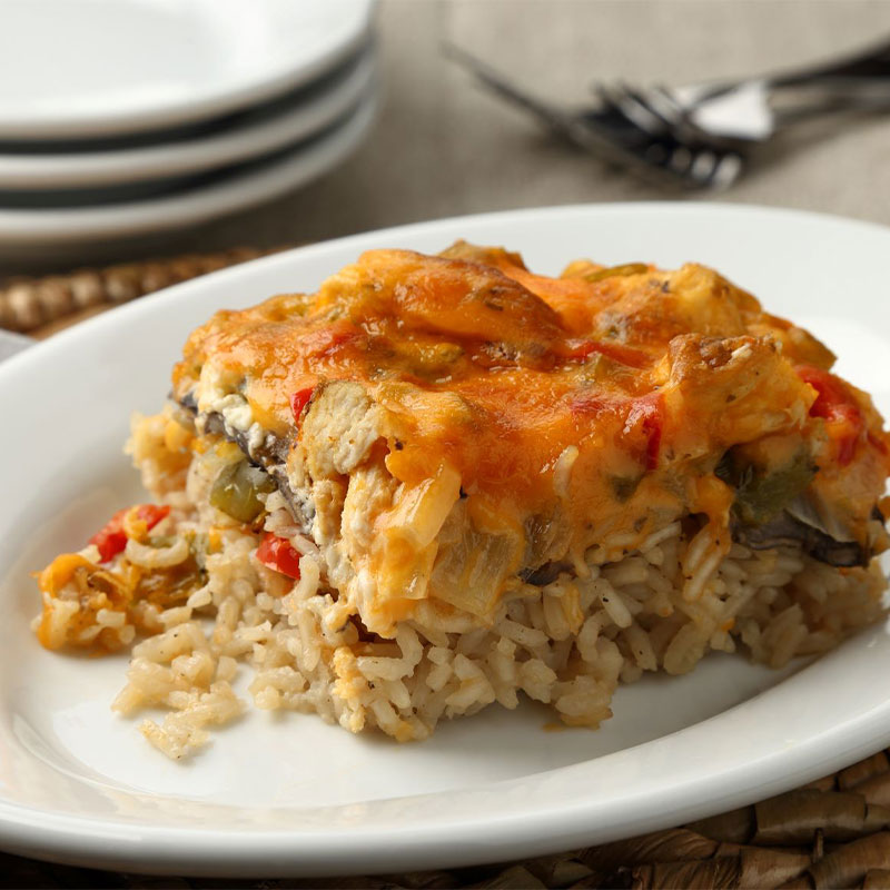 Creamy Chicken Casserole Side shot of a serving of Creamy Cheesy Chicken Rice Casserole on a white plate.