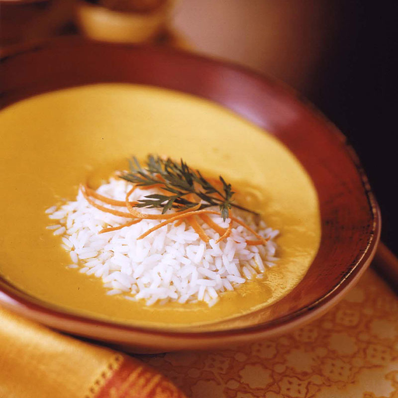 Overhead shot of creamy curry carrot soup with a serving of rice on top.