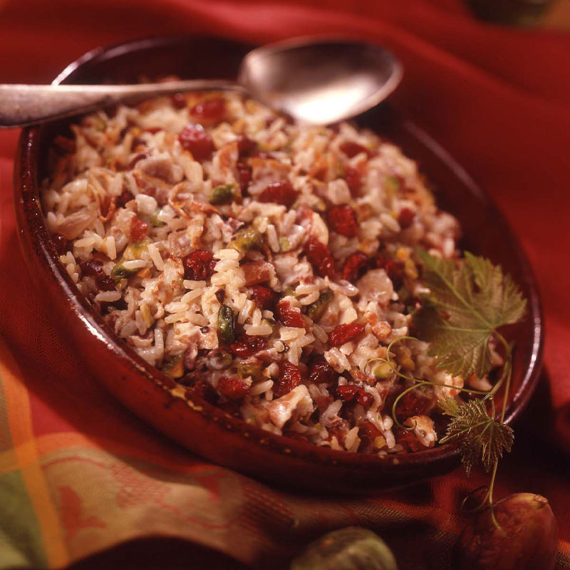 Creamy Pancetta Rice in red dish with a spoon to the side.